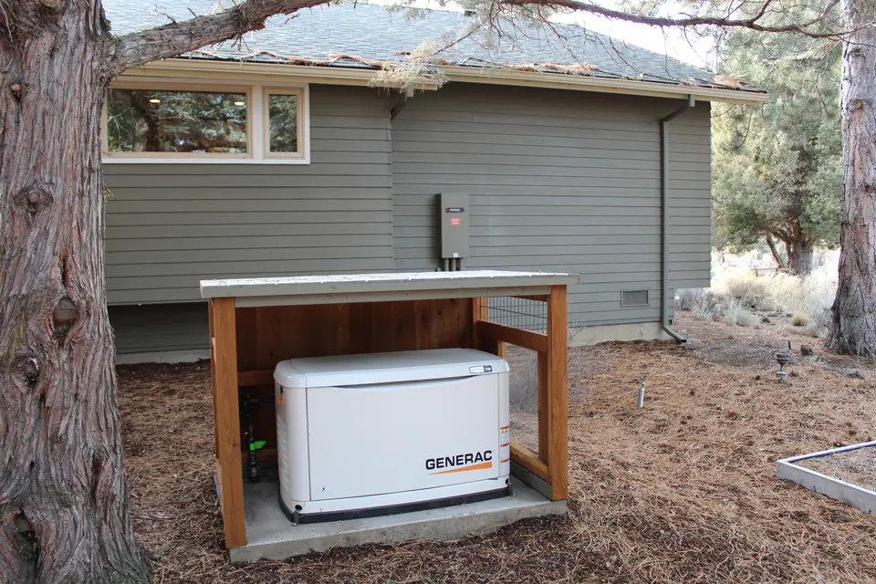 A standby generator in a cedar enclosure beside a home, under pines