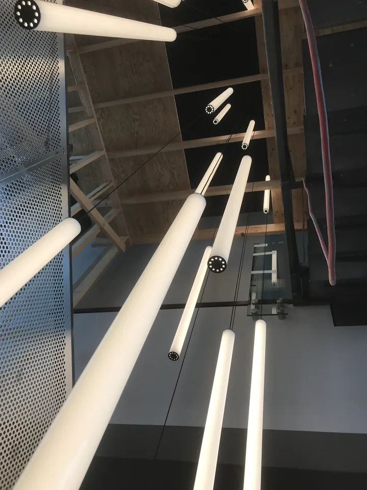 Looking up through a cluster of white pendant tube lights