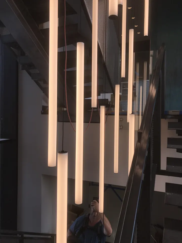 Tall pendant tube lights hanging through a stairwell in a new home