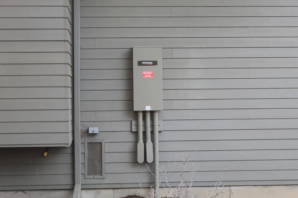 An automatic transfer switch on the gray siding of a house