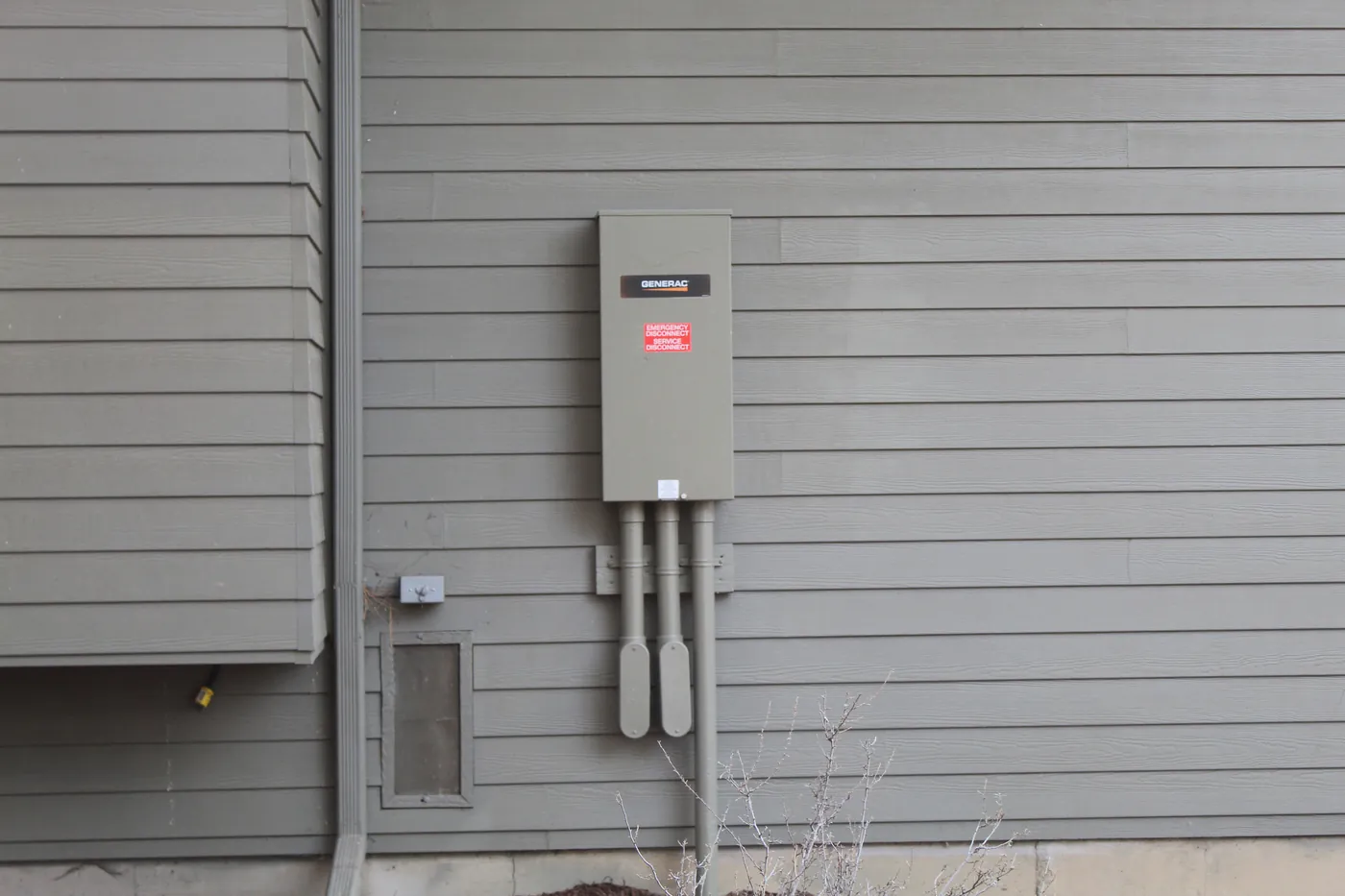 An automatic transfer switch on the gray siding of a house