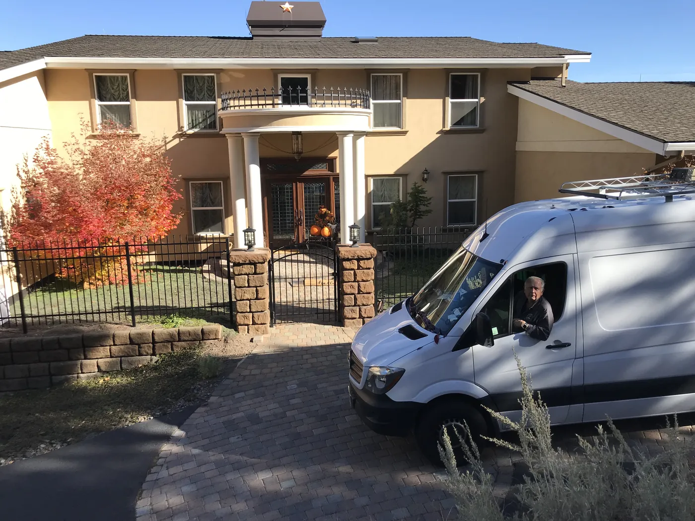 A white work van parked outside a home in autumn